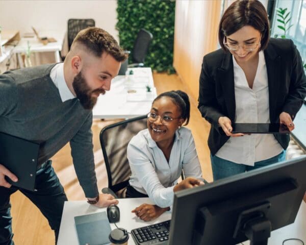 Multicultural team working together on computer and tablet