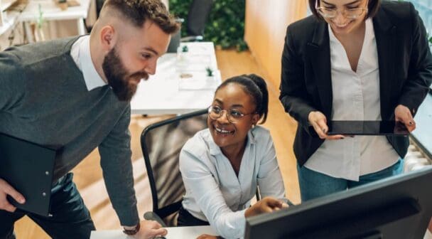 Multicultural team working together on computer and tablet